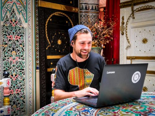 A male English teacher tutoring online while traveling around the world
